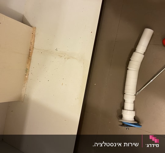 צינור פלסטיק לבן ומברג על הרצפה